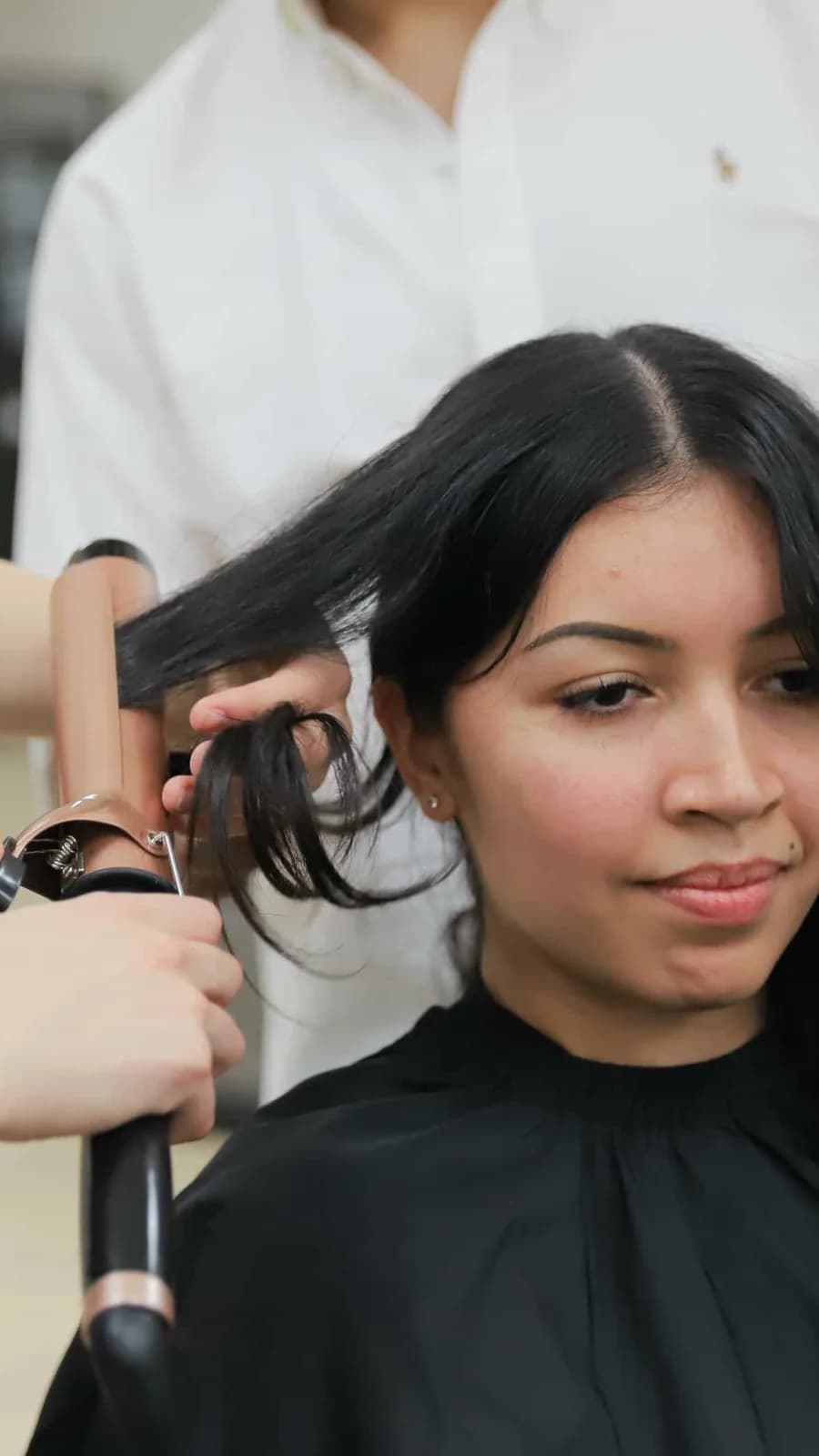Student practising hair curling with an instructor