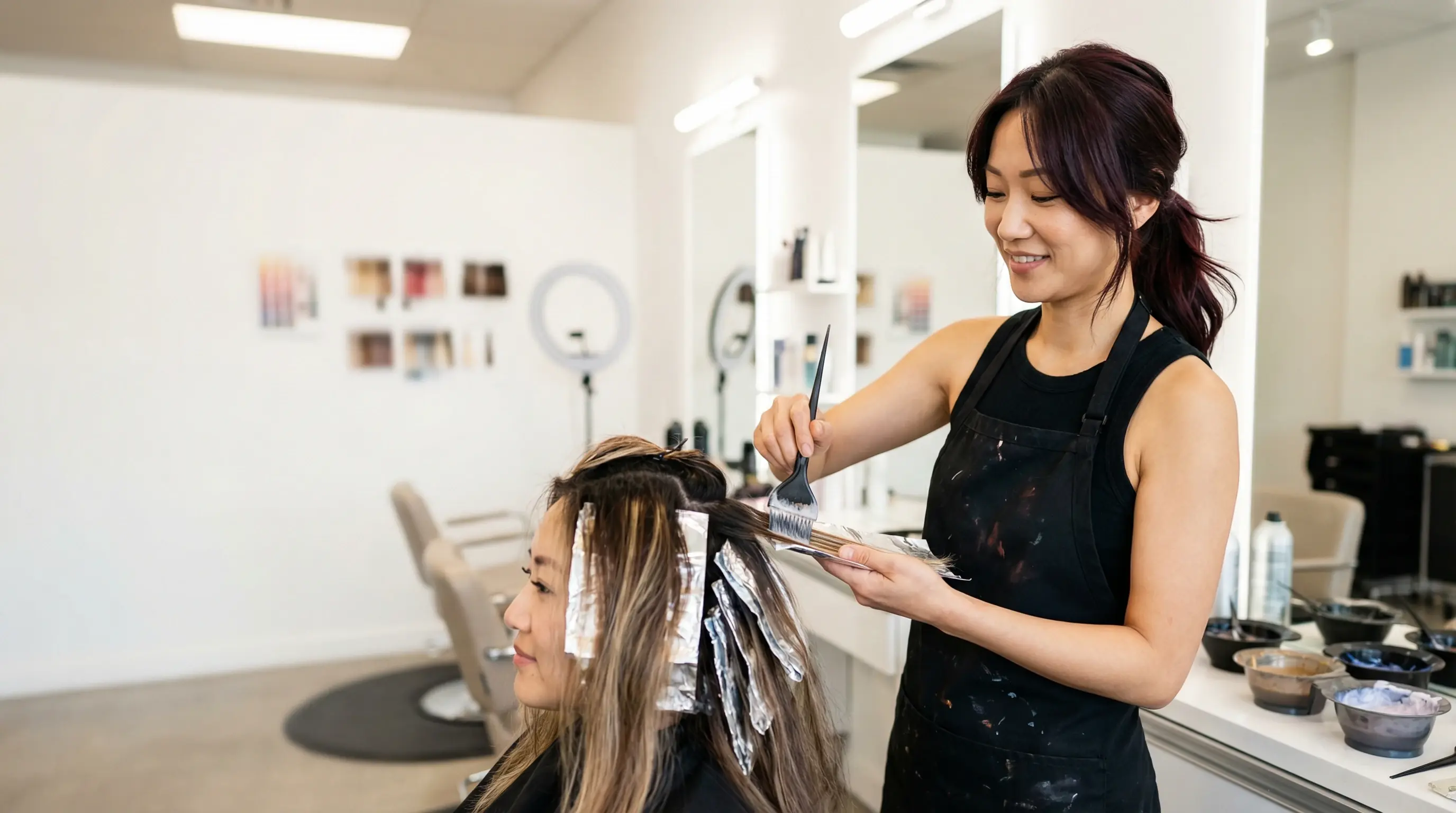 Hairstylist applying balayage color in bright salon
